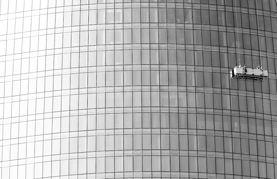 Dramatic shot of window cleaners scaling a glass skyscraper facade.